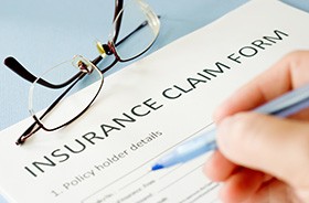 Person using pen to fill out insurance claim form