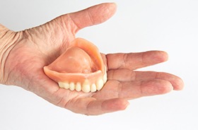 Person holding denture in their hand