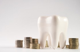 Tooth model next to stacks of coins