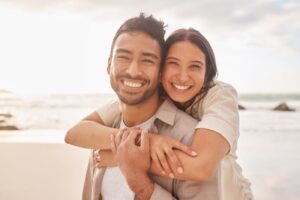 Young couple with beautiful teeth embracing on the beach