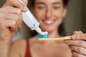 Smiling woman placing toothpaste on toothbrush