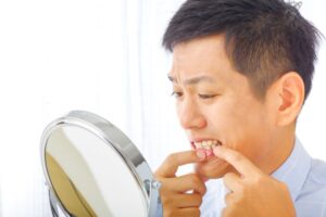 Concerned man looking at his gums in mirror