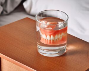 Dentures in glass of water on nightstand 